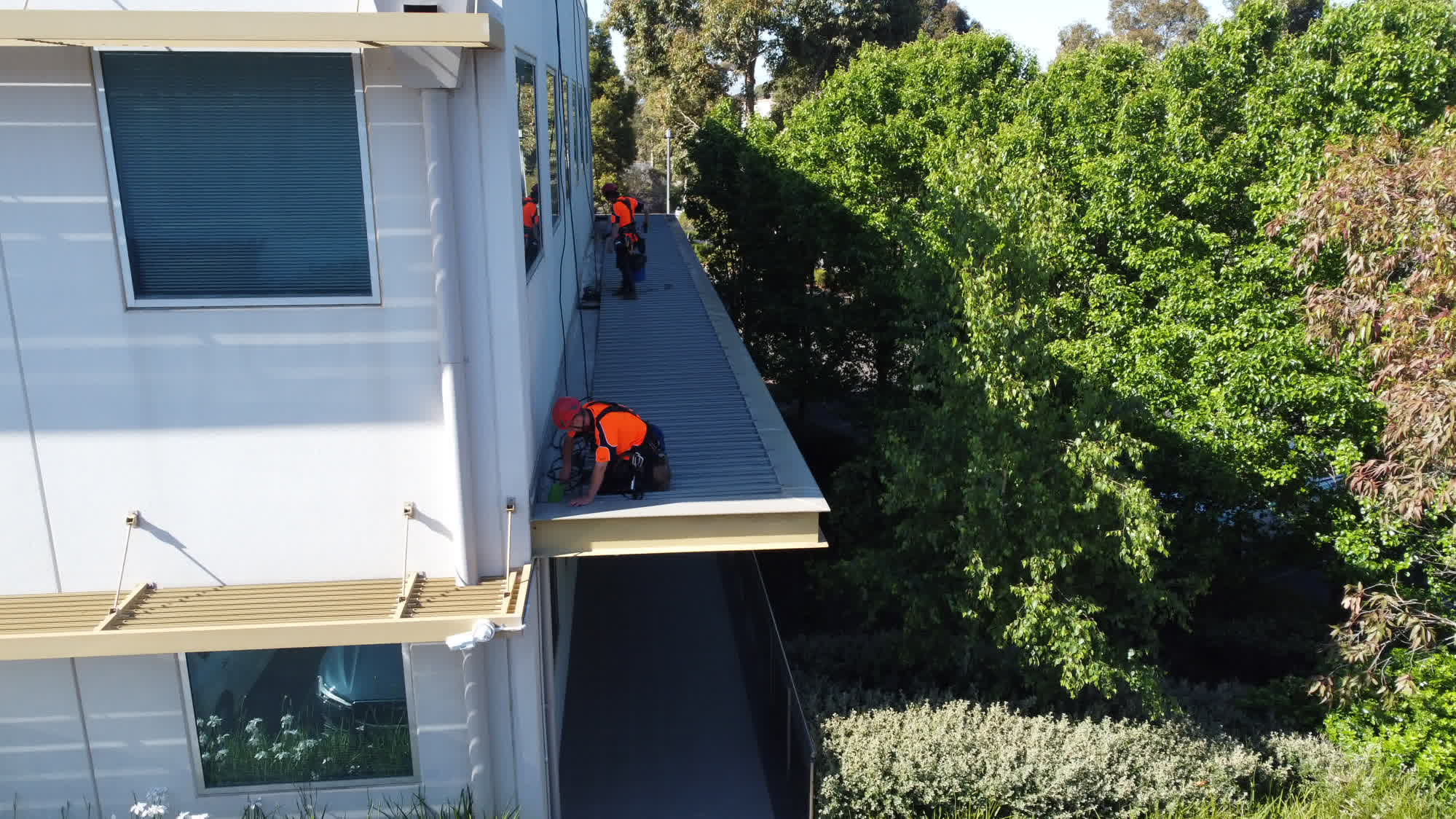 Aerial view of rope access technicians working along a commercial roof edge